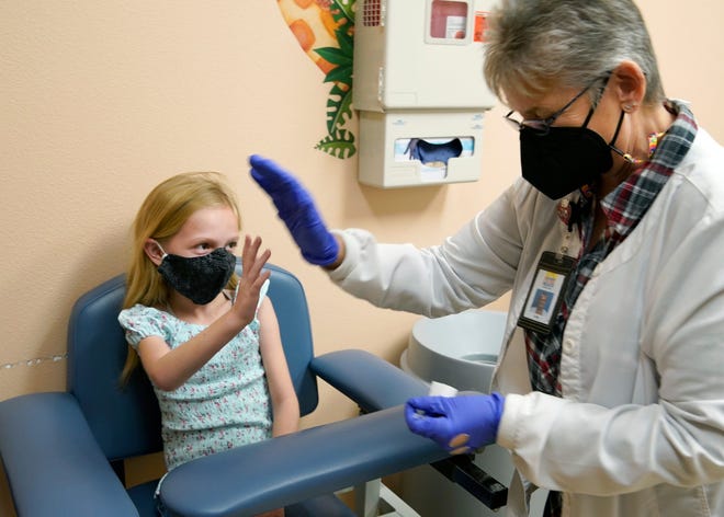 Livia Carbino, 8, gets a high five from her grandmother, registered nurse Livia Gifford, after getting her covid vaccine shot at the Orange City office of the Florida Department of Health in Volusia County on Dec. 3.