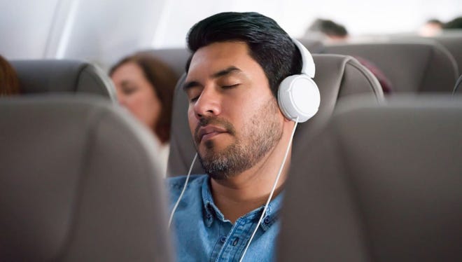Man sleeping on plane with white headphones.