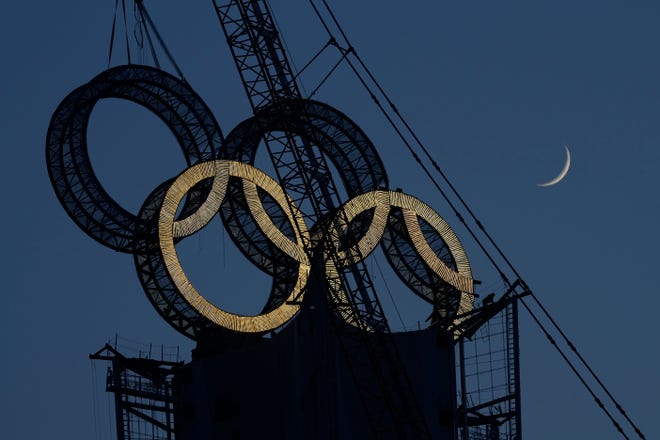 A worker labors to assemble the Olympic Rings onto of a tower on the outskirts of Beijing, China, Wednesday, Jan. 5, 2022. Beijing will host the 2022 Winter Olympics which has numerous events compared to the first Winter Olympics which was held in 1924.