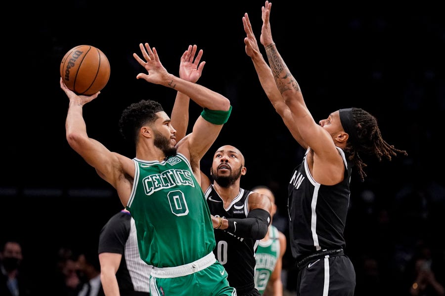 Boston Celtics forward Jayson Tatum (0) passes against Brooklyn Nets guard Patty Mills, right, during the first half of an NBA basketball game, Tuesday, Feb. 8, 2022, in New York. (AP Photo/John Minchillo)