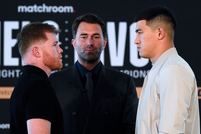 Boxer Canelo Alvarez, left, poses with boxer Dmitry Bivol as promoter Eddie Hern, center, looks on, during a weigh-in in advance of their boxing fight Wednesday, March 2, 2022, in San Diego. Alvarez, of Mexico, is scheduled to fight Bivol, of Russia, in Las Vegas on May 7. (AP Photo/Gregory Bull)