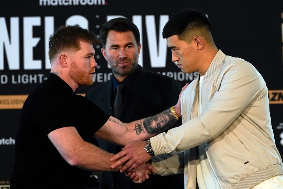 Boxer Canelo Alvarez, left, shakes hands with with boxer Dmitry Bivol as promoter Eddie Hearn looks on, center, during a weigh-in in advance of their boxing fight Wednesday, March 2, 2022, in San Diego. Alvarez, of Mexico, is scheduled to fight Bivol, of Russia, in Las Vegas on May 7. (AP Photo/Gregory Bull)