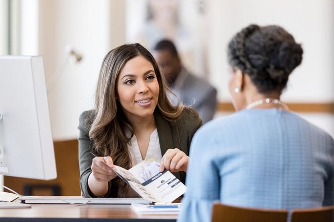 A bank manager helps a woman open up a new account.