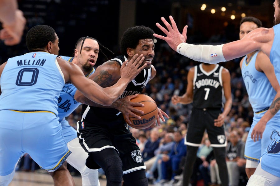 Brooklyn Nets guard Kyrie Irving drives against Memphis Grizzlies guard De'Anthony Melton (0), forward Dillon Brooks (24), and center Steven Adams, right, duribg the first half of an NBA basketball game Wednesday, March 23, 2022, in Memphis, Tenn. (AP Photo/Brandon Dill)