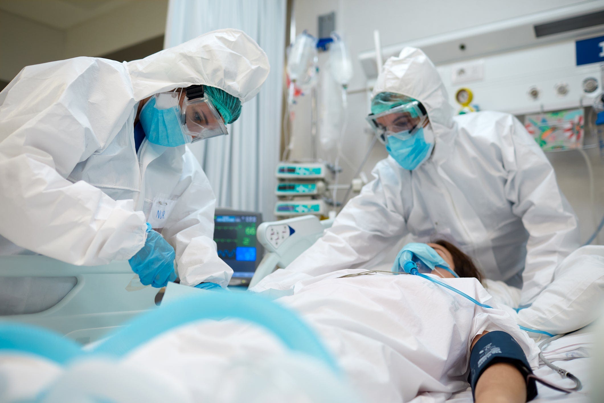 Two heavily protected doctors treat a COVID patient in an ICU.