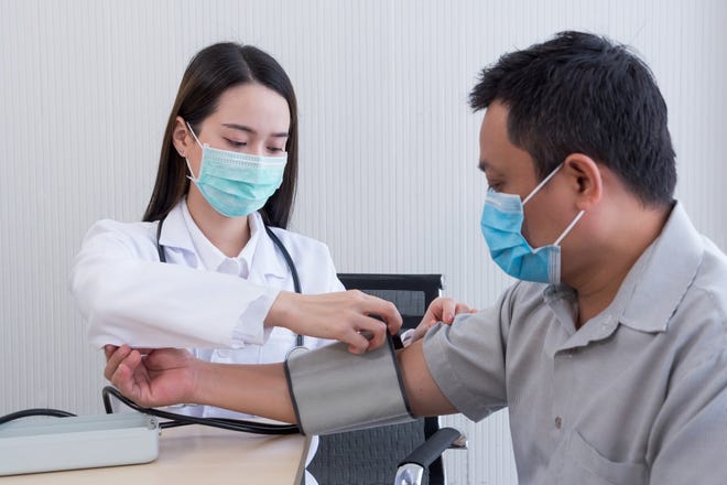A healthcare professional measures a patient's blood pressure.