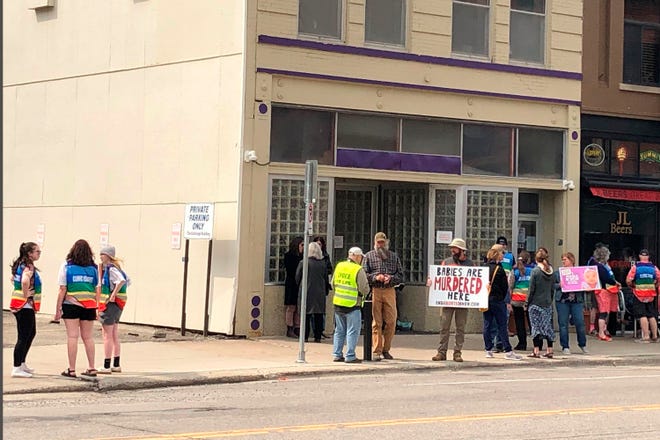 Protesters at North Dakota’s lone abortion clinic are flanked by patient escorts in rainbow-colored vests May 11 in Fargo, N.D.