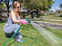 A person watering the grass with a garden hose