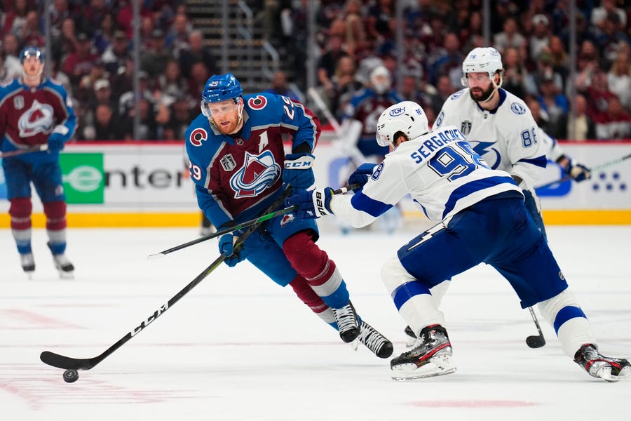Colorado Avalanche center Nathan MacKinnon (29) moves the puck against Tampa Bay Lightning defenseman Mikhail Sergachev (98) during the second period in Game 5 of the NHL hockey Stanley Cup Final, Friday, June 24, 2022, in Denver. (AP Photo/Jack Dempsey)
