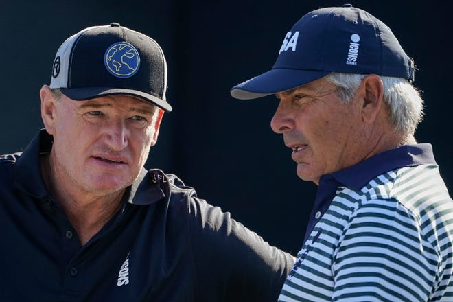 Ernie Els, left, and Fred Couples, right, meet at the first tee during the Icons Series USA 2022 golf tournament, Thursday, June 30, 2022, at Liberty National Golf Course in Jersey City, N.J. (AP Photo/John Minchillo)