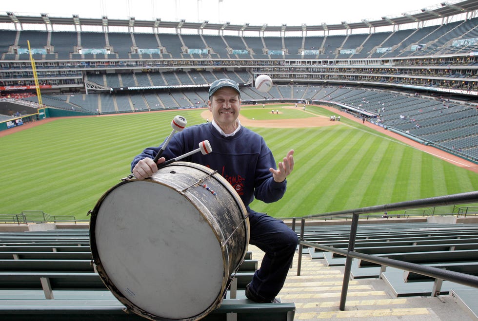 FILE - Cleveland Indians fan John Adams poses in his usual centerfield bleacher seat with his ever-present bass drum before a baseball game between the Indians and the Kansas City Royals on April 27, 2011, in Cleveland. The longtime drummer, who has provided a steady beat during baseball games in Cleveland since the 1970s, has been honored with his induction on Wednesday, Aug. 24, 2022, into the Cleveland Guardians' Distinguished Hall of Fame. (AP Photo/Amy Sancetta, File)