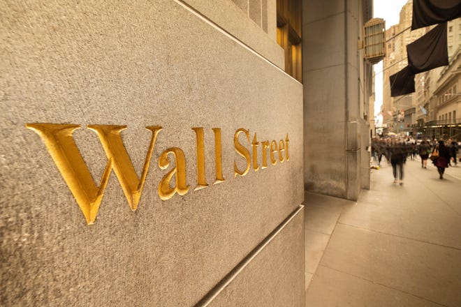 The phrase, Wall Street, etched in gold on the side of a building.