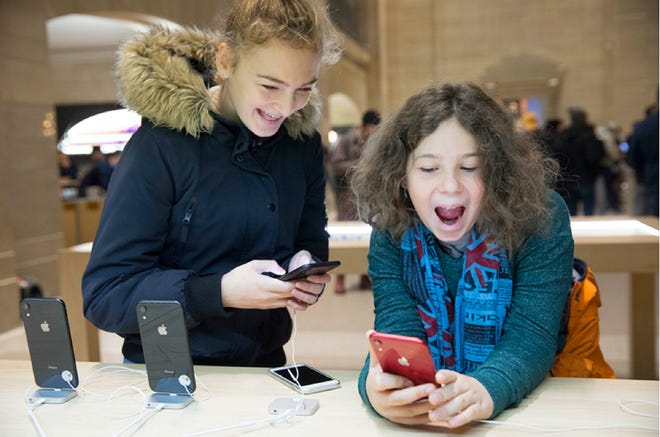 Two visibly excited children playing with display iPhones in an Apple store.