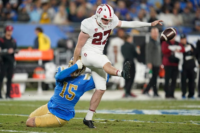 Stanford punter Ryan Sanborn (27) punts while being tackled by UCLA linebacker Laiatu Latu (15) during the second half of an NCAA college football game in Pasadena, Calif., Saturday, Oct. 29, 2022. (AP Photo/Ashley Landis)