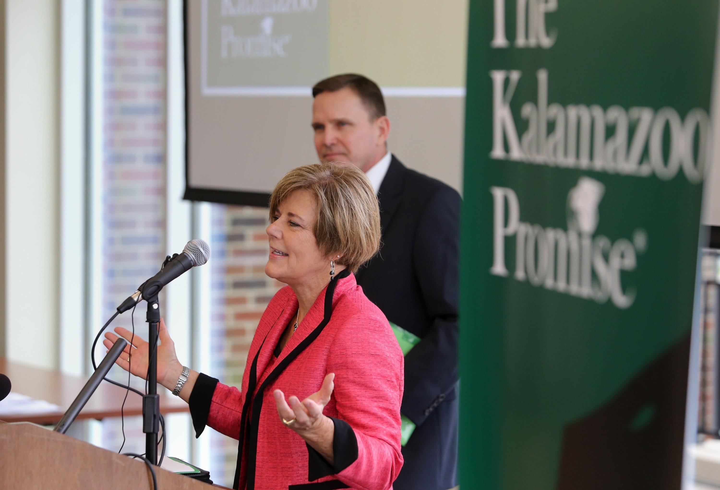 Janice M. Brown, front, board member for the Kalamazoo Promise, speaks as Robert Bartlett, president of the Michigan Colleges Alliance, listens during a news conference in 2014 in Kalamazoo.