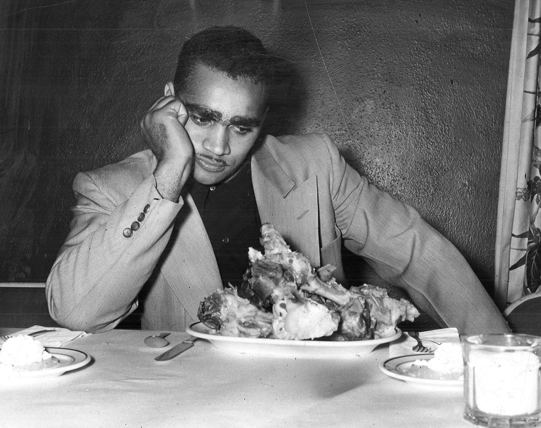 Johnny Bright, the Drake football player whose jaw was wired shut because of a fracture suffered in a 1951 game against Oklahoma A&M, takes a hungry look at a plate full of ham bones just weeks after the assault. The bones were the remains of a huge feed consumed by high school football players in Chariton.