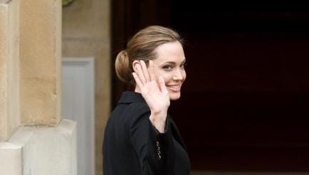 US actress and humanitarian campaigner Angelina Jolie (L) waves as she is greeted by British Foreign Minister William Hague (unseen) outside Lancaster House in central London on April 11, 2013 where she attended a discussion during the G8 Foreign Ministers meeting on the Preventing Sexual Violence Initiative (PSVI). AFP PHOTO / LEON NEAL        (Photo credit should read LEON NEAL/AFP/Getty Images)