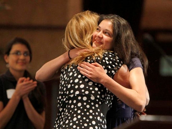 "Miracle Kid" Alyssa Morales, 16, Spencerport, right, hugs her mother, Michelle Morales, after her mother's comments to the audience during the Golisano Children's Hospital's annual Miracle Luncheon held Tuesday, May 21, 2013 at the Riverside Convention Center.