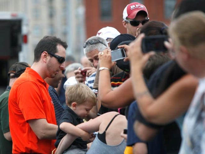 
Left, Kyle Busch signs autographs before driving his car up and down Broad Street in Rochester on Thursday.
