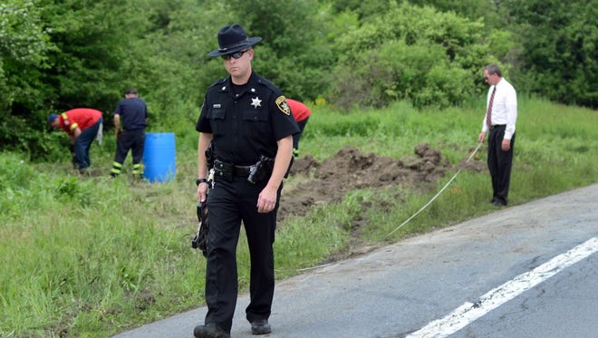 Law enforcement officials work the scene of a fatal car crash along Route 13 in Truxton on Thursday -- the day after seven people were killed when a tractor trailer struck a minivan.