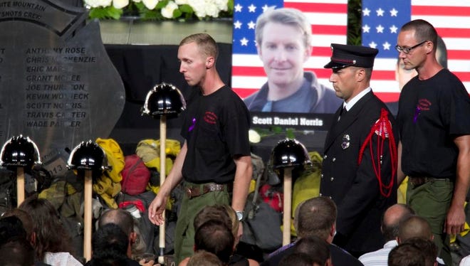 Brendan McDonough, center,  the sole surviving member of the Granite Mountain Hotshots crew takes his seat after saying the "Hotshots Prayer" during the "Our Fallen Brothers" memorial service for the 19 fallen firefighters at Tim's Toyota Center in Prescott Valley, Ariz. on Tuesday, July 9, 2013.   Prescott's Granite Mountain Hotshots were overrun by smoke and fire while battling a blaze on a ridge in Yarnell, about 80 miles northwest of Phoenix on June 30, 2013.   (AP Photo/The Arizona Republic, David Wallace, Pool)