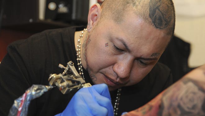 Tattoo artist Nes Andrion works a tattoo on client Crystal Apolinar's arm at the Endless Ink Tattoo & Lounge in Reno, Nevada on Jan. 22, 2013. Andrion is the tattoo artist who did  49ers quarterback Colin Kaepernick's tattoos.
