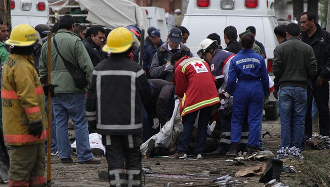 Firefighters, investigators and forensic personnel pick the corpse of one of at least eleven victims of an explosion in Jesusito Nativitas, Tlaxcala, Mexico, Friday.