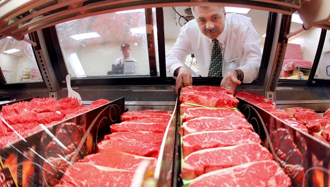 Mike Hoffman, meat manager for Dahl's Foods in Des Moines, loads a fresh platter of steaks into the beef case at the Merle Hat Road location on Feb. 7, 2013.