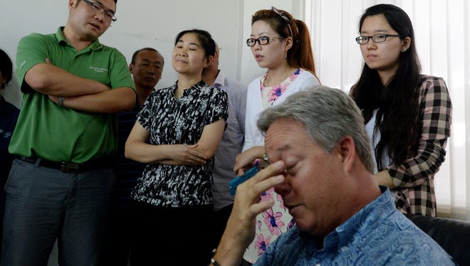 U.S. businessman Chip Starnes (sitting), who was held hostage for six days over a wage dispute, is surrounded by government officials and trade union leaders during a briefing at his Specialty Medical Supplies business in Huairou, Beijing on June 26, 2013.