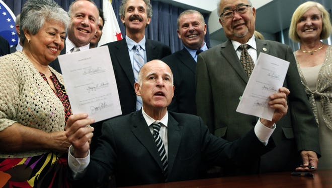 California Gov. Jerry Brown, with business leaders, holds the pension legislation he signed last month.