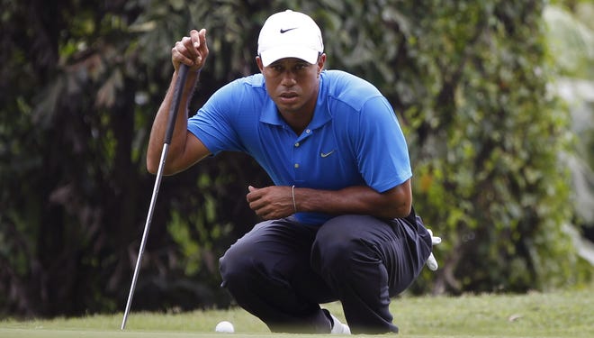 Tiger Woods lines up a putt on the third hole during the CIMB Classic golf tournament.