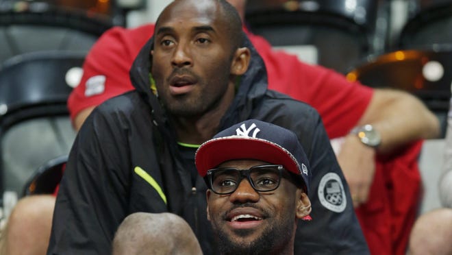 LeBron James, with hat, and Kobe Bryant watch the U.S. women's basketball team play Canada at the 2012 Summer Olympics. 