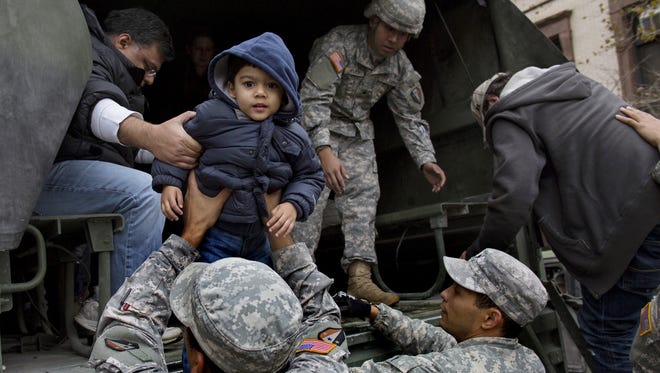 Vihaan Gadodia, 2, is handed from a National Guard truck after he and his family left a flooded building in Hoboken, N.J., Wednesday in the wake of superstorm Sandy.