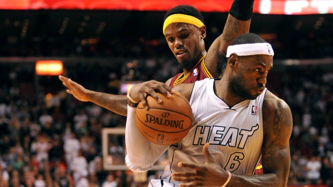 Heat forward LeBron James drives past former teammate Daniel Gibson of the Cavaliers during a 110-108 win Saturday.