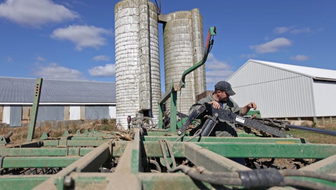 Brandon Bonk makes an adjustment on his tractor which is equipped with GPS technology,  in Dover, Del., on Oct. 16. "The tractor's driving itself, and it makes it so much easier not having to worry about keeping a straight line or holding a steering wheel. It's virtually stress free," Bonk said.