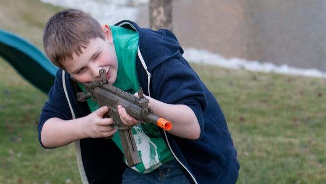 Alex Vandiver, 10, plays with a toy gun in the back yard of his home in Fishers, Ind., on Tuesday, Dec. 18, 2012.