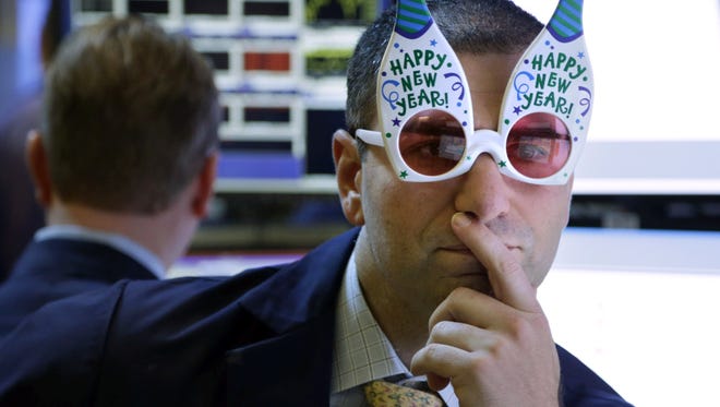 A trader wearing "Happy New Year" glasses works on the floor at the New York Stock Exchange on Monday.