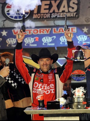 Tony Stewart (14) celebrates in victory lane with a pair of six shooters after winning the AAA Texas 500 at Texas Motor Speedway on Nov 6, 2011.