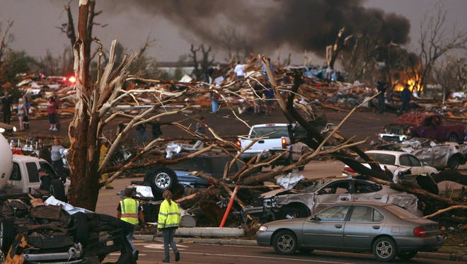 In this 2011 file photo, emergency personnel walk through a severely damaged neighborhood after a tornado hit Joplin, Mo. As tornado season nears, scientists are still trying to figure out if there be more or fewer tornadoes as global warming increases.