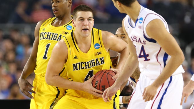 Michigan forward Mitch McGary (4) looks to pass against the defense of Kansas Jayhawks forward Perry Ellis (34) during the second half of the South Region semifinal on Friday in Arlington, Texas.