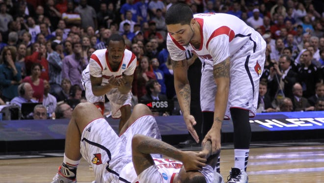 Louisville Cardinals players Chane Behanan (bottom) , Peyton Siva (right) and Russ Smith react after an injury suffered by teammate Kevin Ware (not pictured) in the first half during the finals of the Midwest regional of the 2013 NCAA tournament against the Duke Blue Devils at Lucas Oil Stadium.