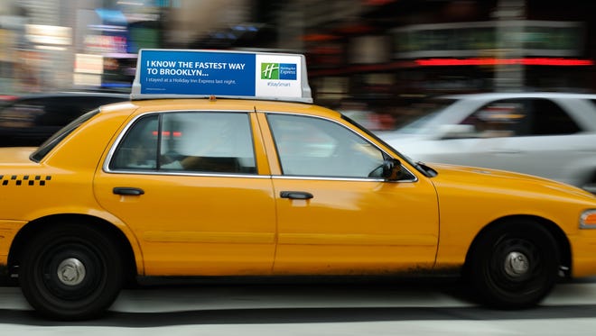 A Holiday Inn Express billboard rides around New York's Times Square on the roof of a cab.
