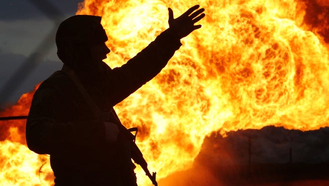 A Chechen police officer watches as flames rage from an oil well outside Grozny, Chechnya, on Nov. 18, 2006. Homemade bombs exploded in two oil wells, and a third device was found in another well in what authorities said they suspected was an attack by rebels.