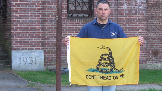 Peter Parente, president of the United Veterans Memorial and Patriotic Association, holds a Gadsden flag outside an armory in New Rochelle, N.Y., on April 26, 2013.