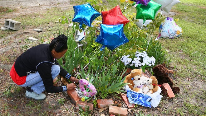 Vanessa Gibson leaves balloons Thursday, April 25 at a memorial in front of mobile home where four children were killed in a fire the day before in Hartsville, S.C.