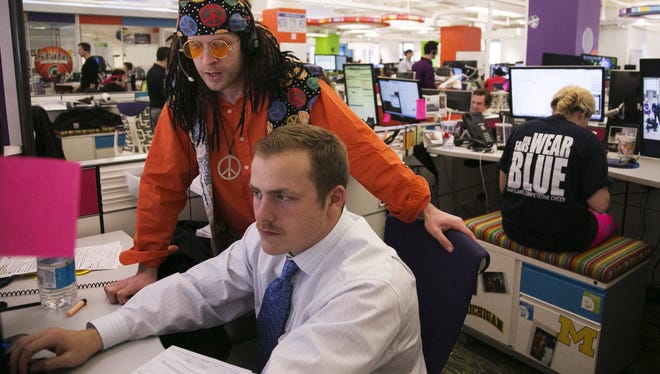 Quicken Loans mortgage banker Ryan Lammers stands over Joe Bagersotck, director of mortgage bankers, at the Quicken Loans office n downtown Detroit on Monday April 22, 2013. Lammers was dressed up as a hippie as part of contest for employees dressing in attire from different decades.