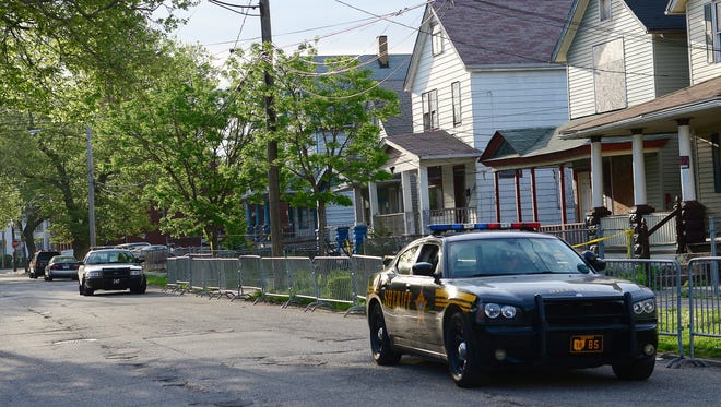 Police patrol cars stand watch in front of the house where three women were held captive for a decade in Cleveland.