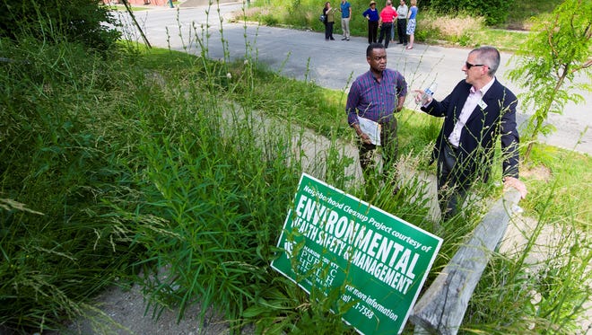 James A. Whitfield, left, of the Highland Vicinity Neighborhood Association, and Michael Osborne, president of Near North Development Corp., discuss a property that sits buried in an overgrown lawn.