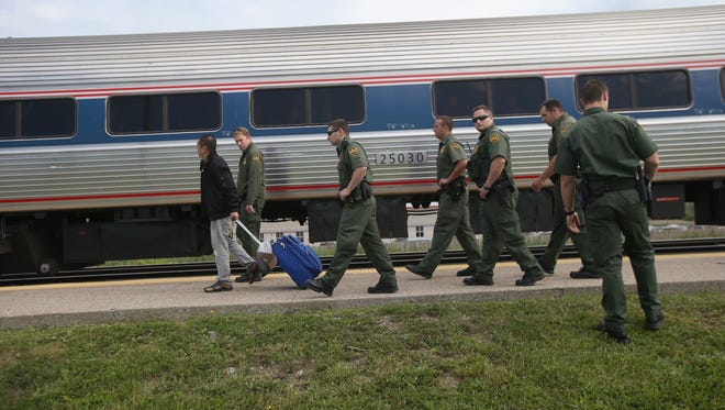 Border Patrol agents escort an individual without identification Wednesday in Depew, N.Y., after checking for undocumented immigrants on an Amtrak train from Chicago.