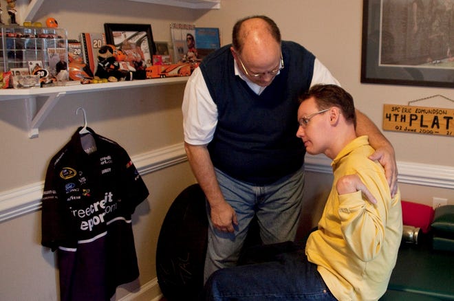 Ed Edmundson helps his son Eric Edmundson sit in exercise room in their home in New Bern, N.C. More families are caring for loved ones at home, and they're relying on the Internet for help.